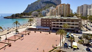 A coastal urban area with a prominent mountain, a beach, and a multi-story building with balconies. - 16sapphire first line (Calp)