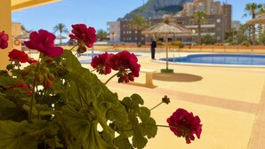 A pool area with a mountain view, surrounded by greenery and a yellow structure. - 16sapphire first line (Calp)