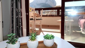 A balcony with a wooden table, two potted plants, and a view of a mountain. - 16sapphire first line (Calp)