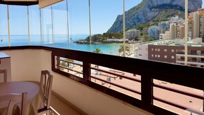 A balcony with a view of a beach, a mountain, and coastal buildings. - 16sapphire first line (Calp)