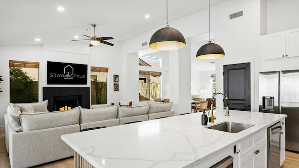 Una cocina moderna con una isla grande, armarios blancos e iluminación colgante.