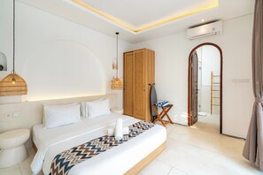 A modern hotel room with a large bed, bedside lamps, a wardrobe, and an air conditioning unit.