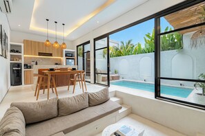 A modern interior with a dining area, kitchen, and a poolside seating area. - Yahvi Villa by Betterplace (Canggu)