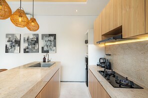 A modern kitchen with a central island, stainless steel appliances, and wooden cabinets. - Yahvi Villa by Betterplace (Canggu)