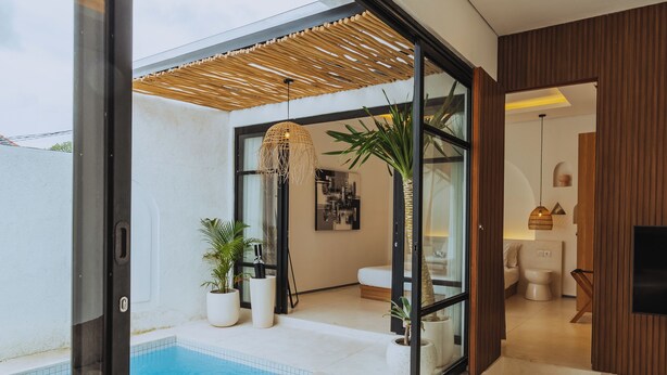Een moderne binnenzwembadruimte met glazen wanden, een houten plafond en potplanten.