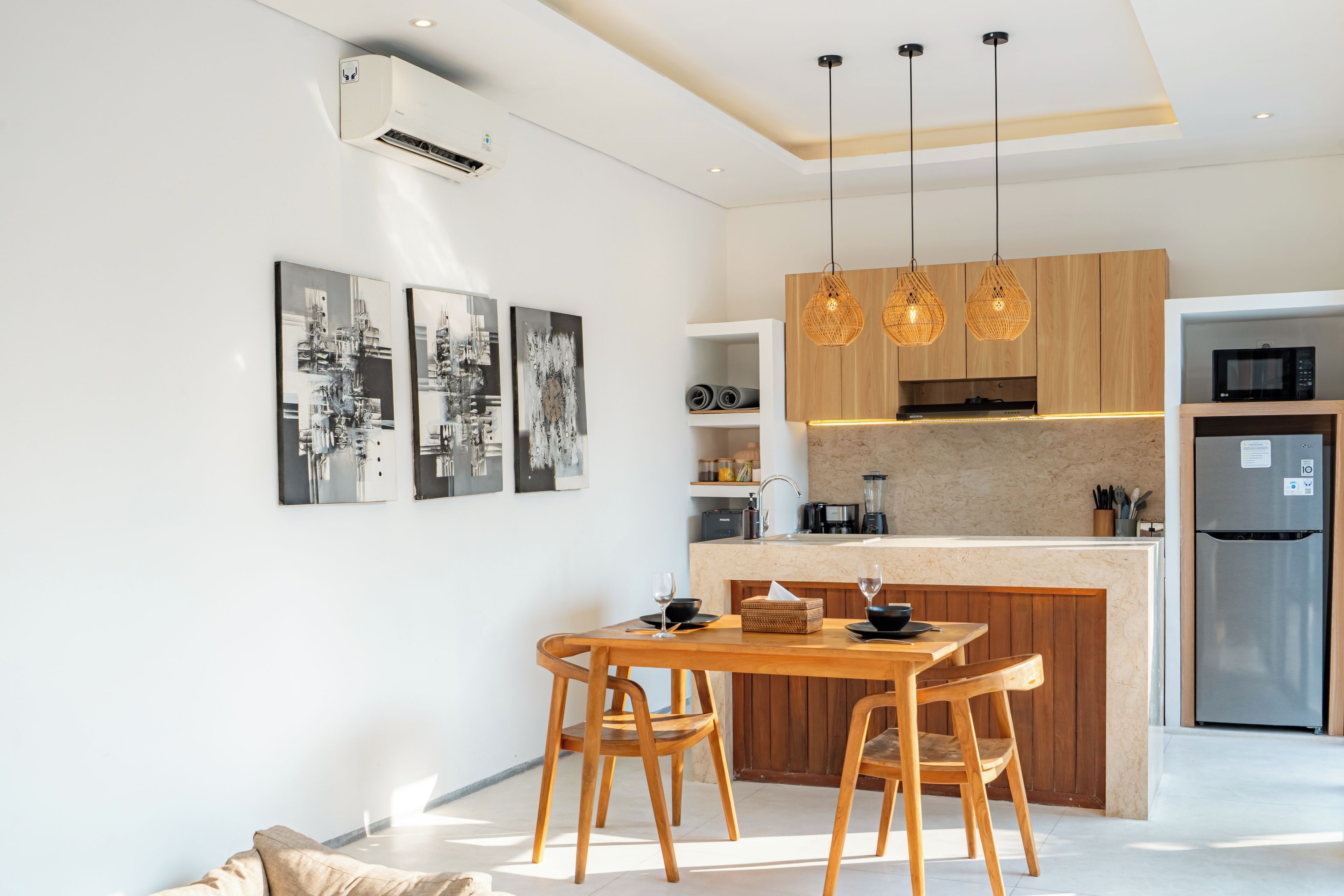 Une cuisine moderne avec un îlot central, des chaises en bois et des luminaires suspendus.