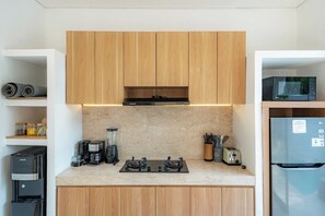 A modern kitchen with wooden cabinets, a built-in microwave, a refrigerator, a coffee maker, and a blender.