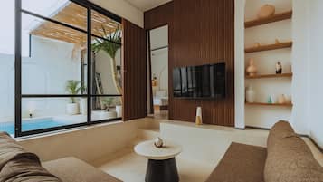 Uma sala de estar moderna com uma janela ampla, uma TV de tela plana e um painel de parede em madeira.