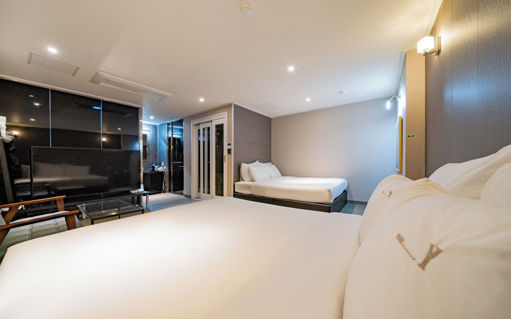 Habitación de hotel moderna con una cama grande, un escritorio, un televisor de pantalla plana y una puerta corredera que da a un baño.