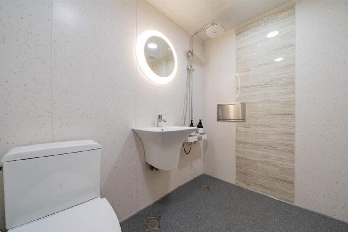 A modern bathroom with a toilet, a sink with a mirror, and a shower.