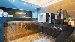A modern coffee bar with a counter labeled "Coffee Time," equipped with a coffee machine, a microwave, and various coffee-related items. - ymotel (Busan)