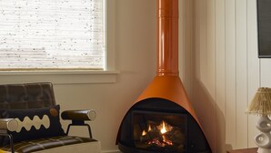 A cozy living room with a fireplace, a sofa, a table with sunflowers, and a lamp. - NEW Wellness Focused Adult Only Boutique Hotel - Premium Suite w Gas Fireplace (Rodanthe)
