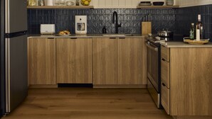 Una cocina moderna con armarios de madera, horno empotrado, cafetera y pileta.