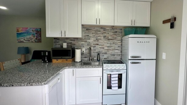 A compact kitchen with white cabinets, a built-in microwave, a stove, and a Galanz refrigerator. - Turtle Nest 2 - Quick Walk to Beach (Fort Myers Beach)
