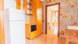 Una cocina compacta con un refrigerador blanco, armarios de madera y salpicadero de azulejos.
