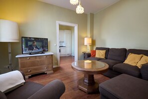 Un salon avec un téléviseur, un canapé et un coin repas à l’arrière-plan.