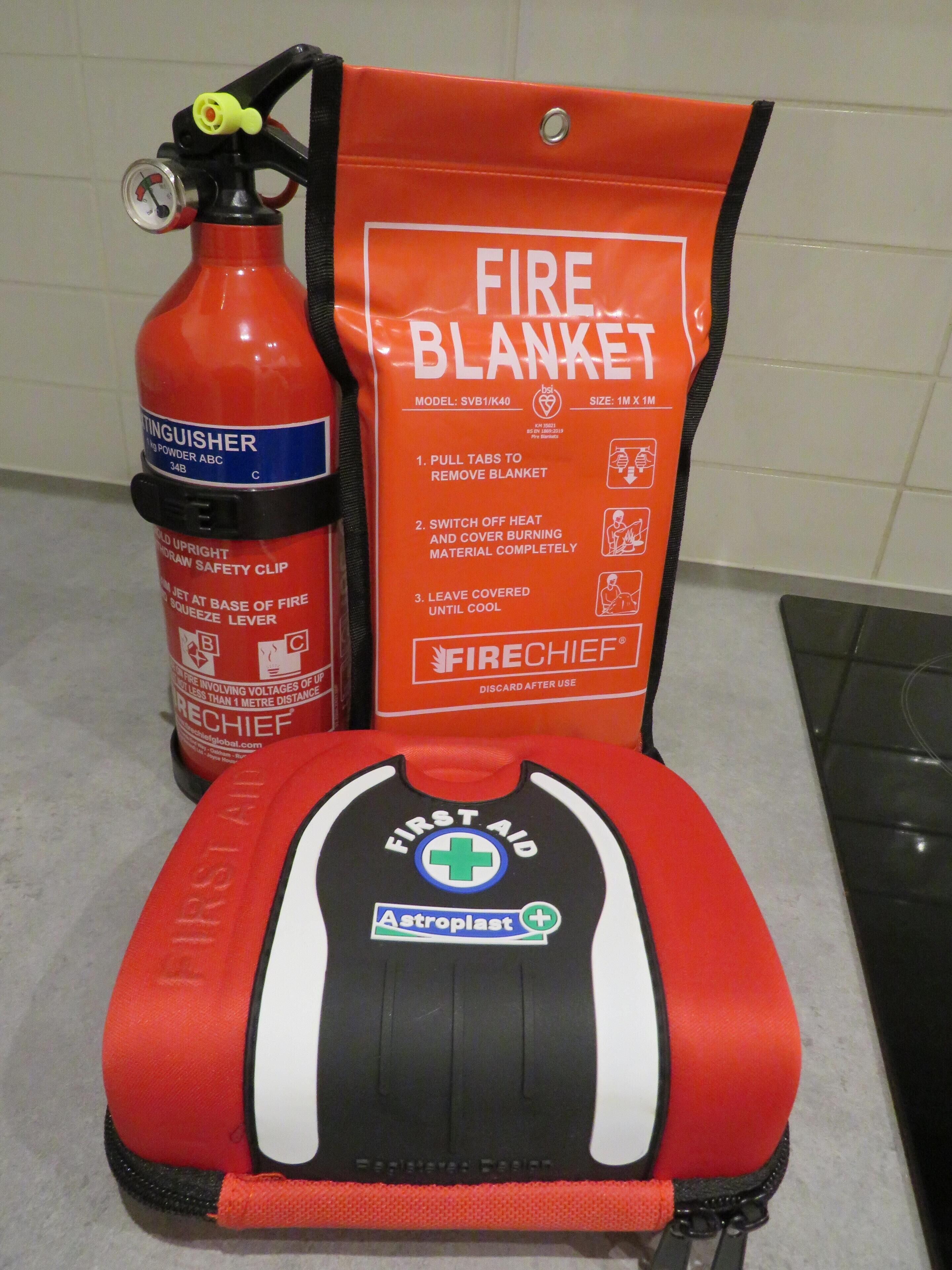 Ein Feuerlöscher, eine Löschdecke und eine Erste-Hilfe-Ausrüstung auf einer Arbeitsplatte.