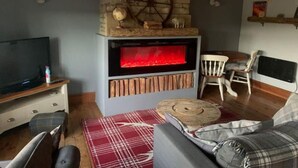 A cozy living room with a stone fireplace, a television, and a comfortable seating area. - Stunning 1-Bed Cottage in Halifax (Halifax)