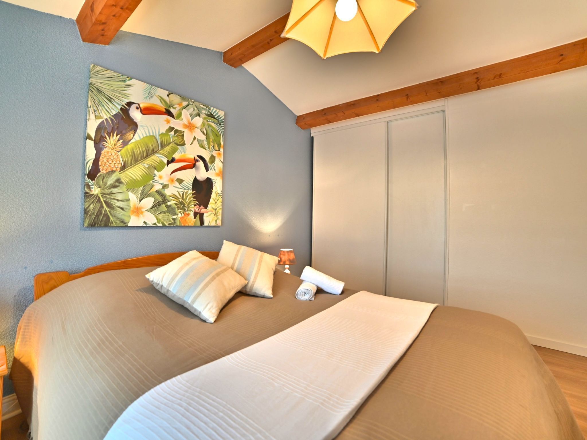 Une chambre à coucher avec un lit, des oreillers, une lampe, un tableau et une armoire.