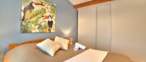 Une chambre à coucher avec un lit, des oreillers, une lampe, un tableau et une armoire.