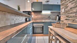 A modern kitchen with a central island, a built-in oven, and a stainless steel sink. - Les coutures by Interhome (Ile d'Oléron)
