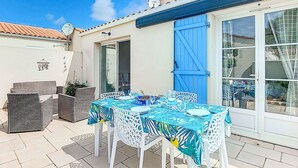 An outdoor patio with a table set for two, surrounded by wicker furniture. - Les coutures by Interhome (Ile d'Oléron)