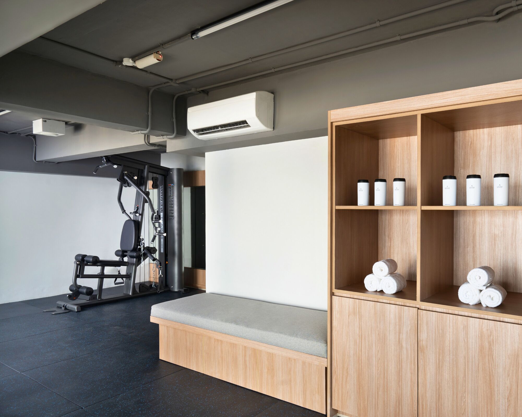 Ein Fitnessraum mit Trainingsgeräten und einer Holzeinrichtung mit Flaschen.