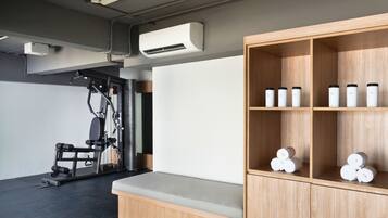 Ein Fitnessraum mit Trainingsgeräten und einer Holzeinrichtung mit Flaschen.