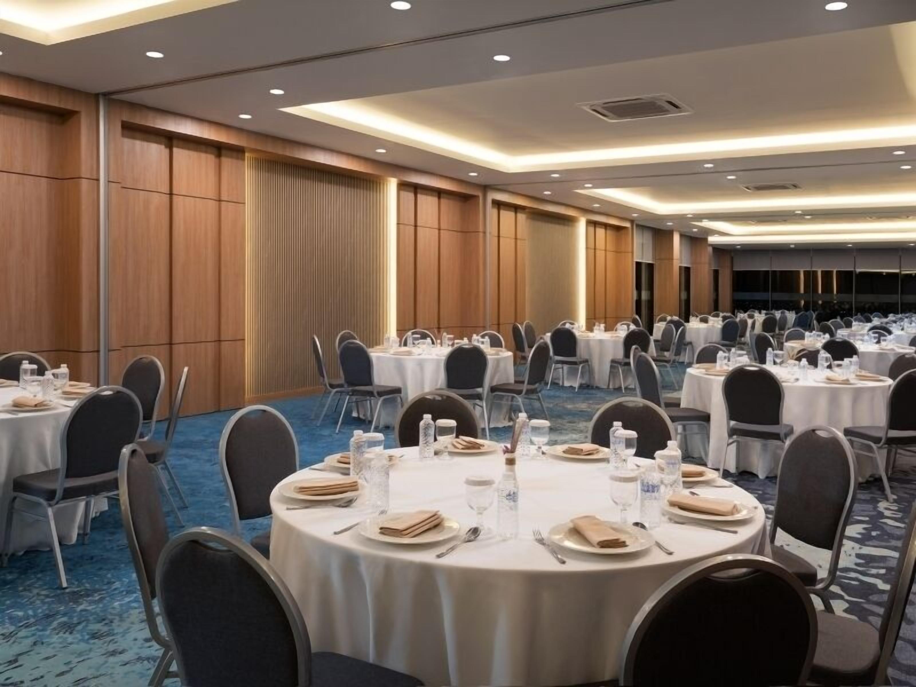 A conference room with round tables, chairs, and tables set for a meal.