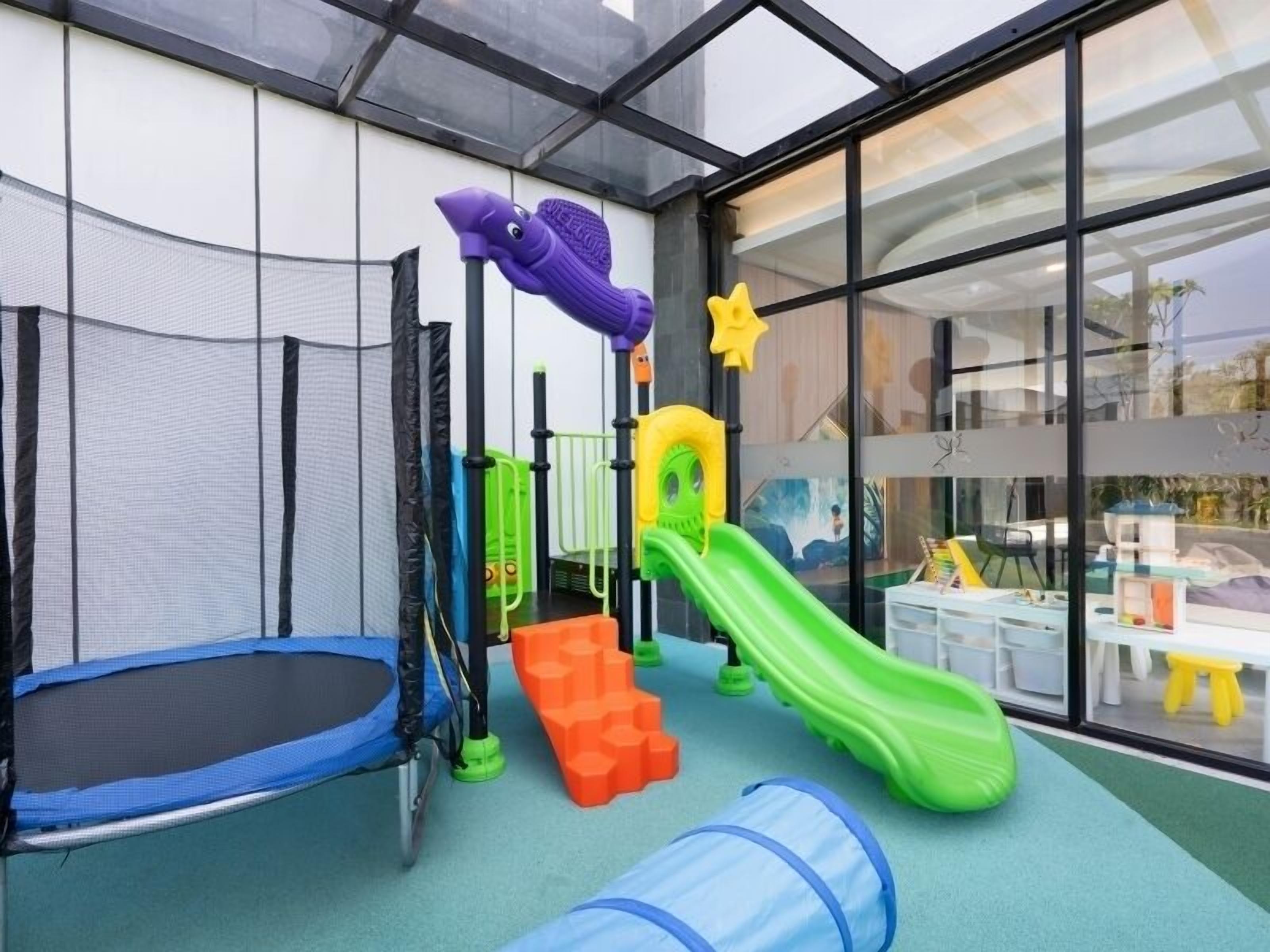 A children's play area with a trampoline, slides, and climbing structures.