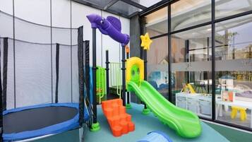 A children's play area with a trampoline, slides, and climbing structures.