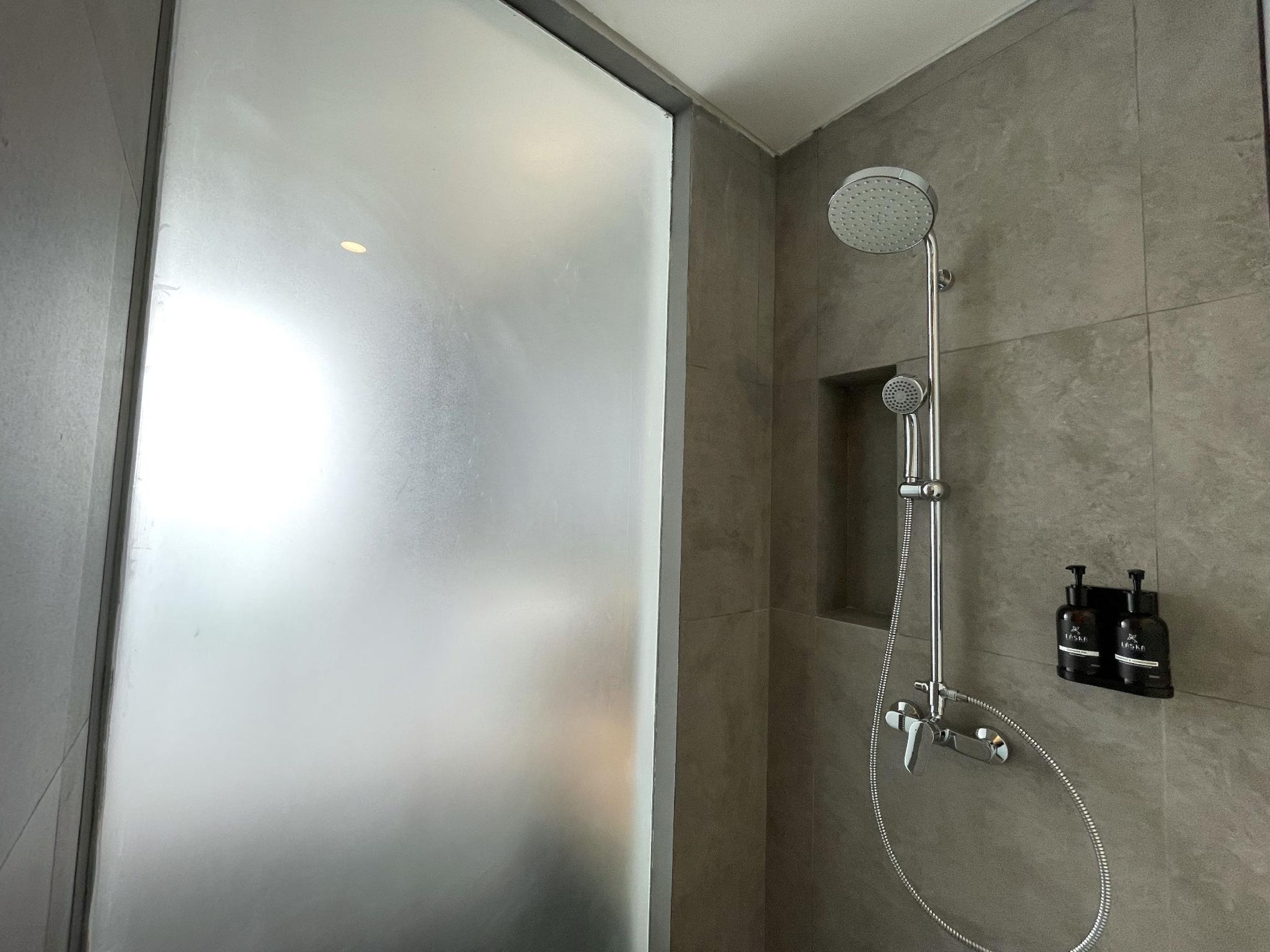 A modern shower with a handheld showerhead and a wall-mounted control panel.