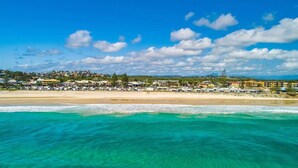 A coastal town with a beach, clear turquoise waters, and a variety of buildings in the background. - Luxury coastal retreat only 250m from the beach! (Tweed)