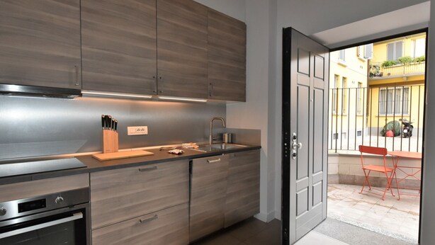 A modern kitchen with wooden cabinets, a stainless steel range hood, and a built-in oven. - Gluck Central Station Lofts by Interhome (Milan)