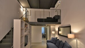 A modern living space with a staircase, a sofa, a bookshelf, a dining area, and a balcony. - Gluck Central Station Lofts by Interhome (Milan)