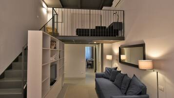 Ein moderner Wohnraum mit Treppe, Sofa, Bücherregal, Essbereich und Balkon.
