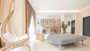 A modern living room with a hanging chair, a sofa, and a kitchen area in the background. - The Duyong Dream (Malacca City)