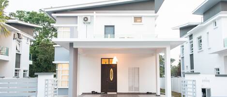 A modern two-story building with a prominent entrance, a balcony, and a well-lit interior.