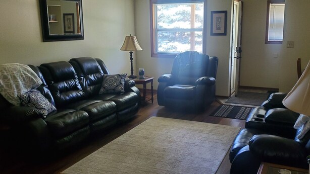 A living room with a black leather sofa, a matching armchair, a coffee table, and a lamp.