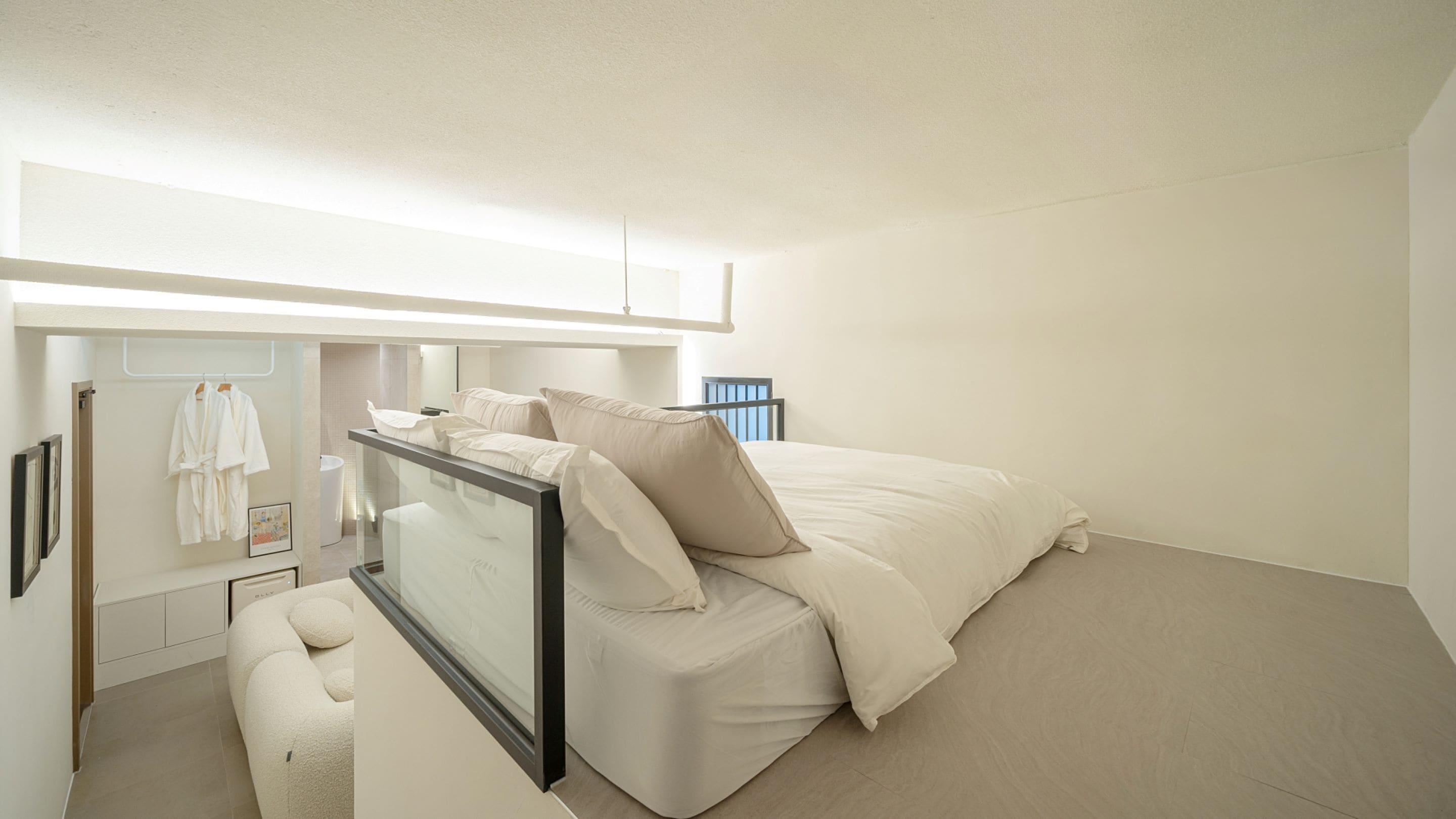Quarto moderno com cama, um banquinho e um espelho.