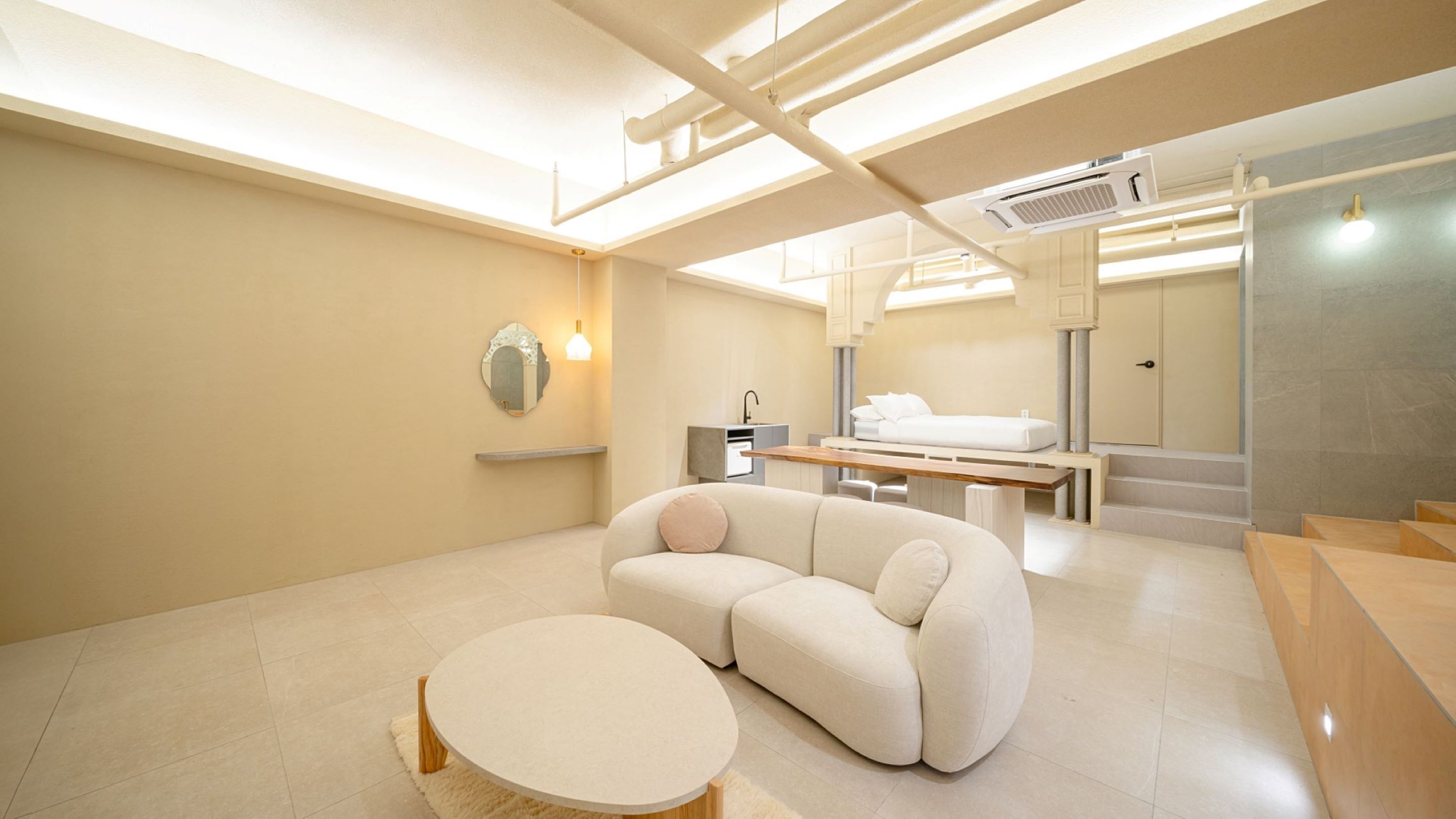 Une chambre d’hôtel moderne équipée d’un canapé, d’une table ronde, d’un lit et d’une salle de bain avec douche et toilettes.