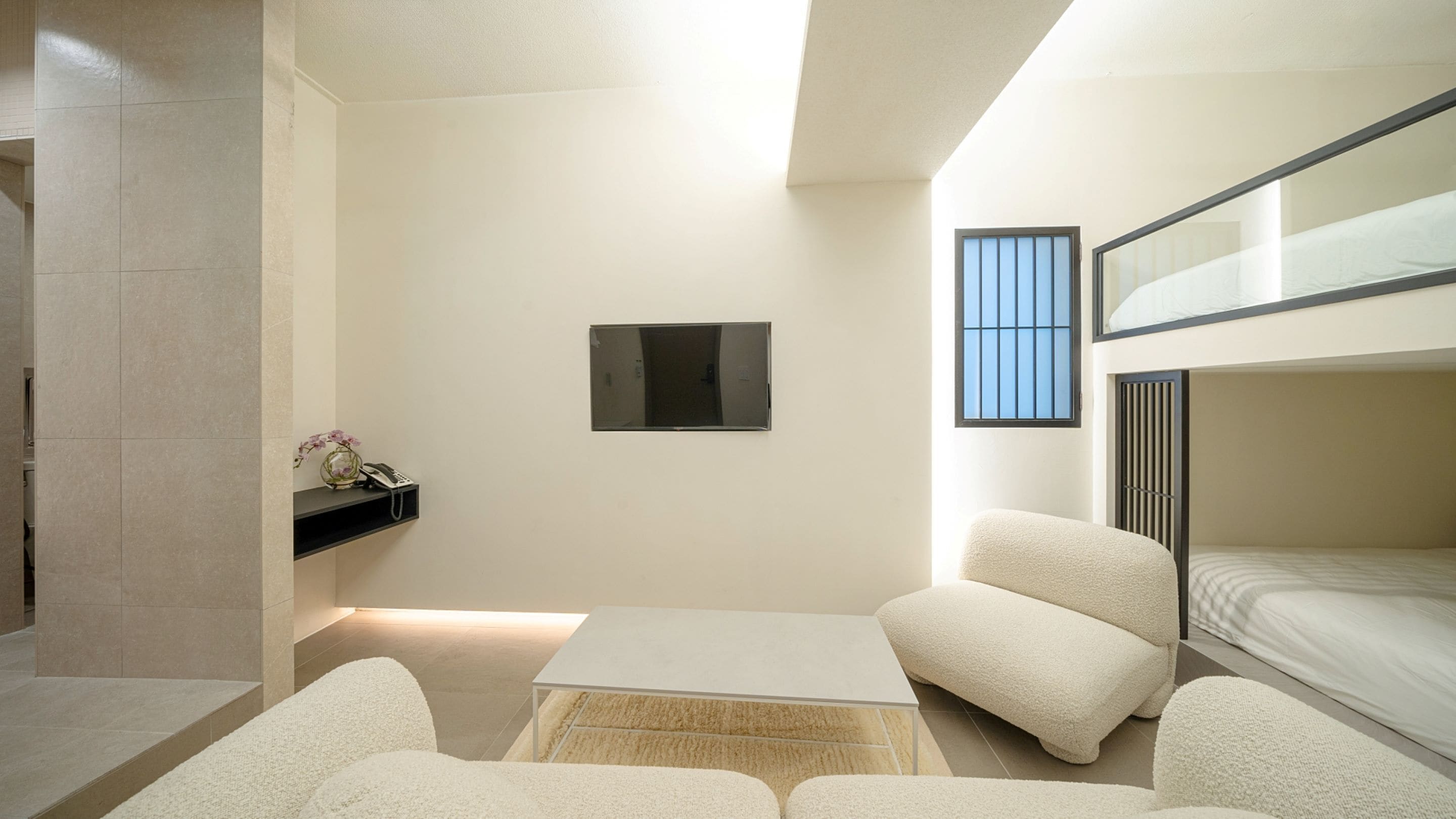 A compact, modern room with a bunk bed, a small table, and a chair.