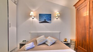 Ein Schlafzimmer mit einem großen Bett, zwei Nachttischlampen, einem Nachttisch, einem Holzschrank und einem Bild an der Wand.