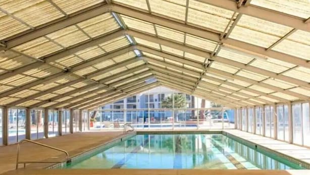 Ein überdachter Pool mit Glasdach und Blick auf die umliegenden Gebäude.