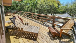 Une terrasse en bois, agrémentée de tables et de chaises pour pique-niquer, entourée d’arbres.