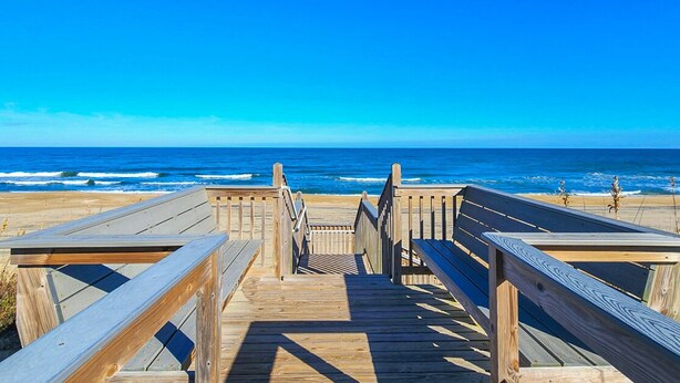 Une promenade en bois qui mène à la plage et offre une vue dégagée sur l’océan.