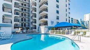 Um hotel com piscina, várias varandas e área de estar coberta.