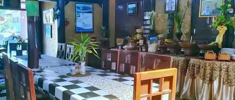 A restaurant with a checkered tablecloth, wooden chairs, and a tiled floor.