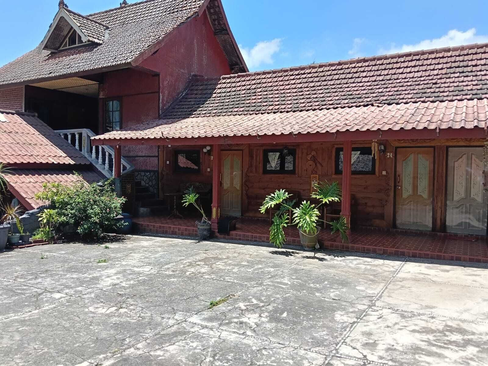 Una casa de madera tradicional con techo de tejas, un porche cubierto y una escalera que conduce a un nivel superior.