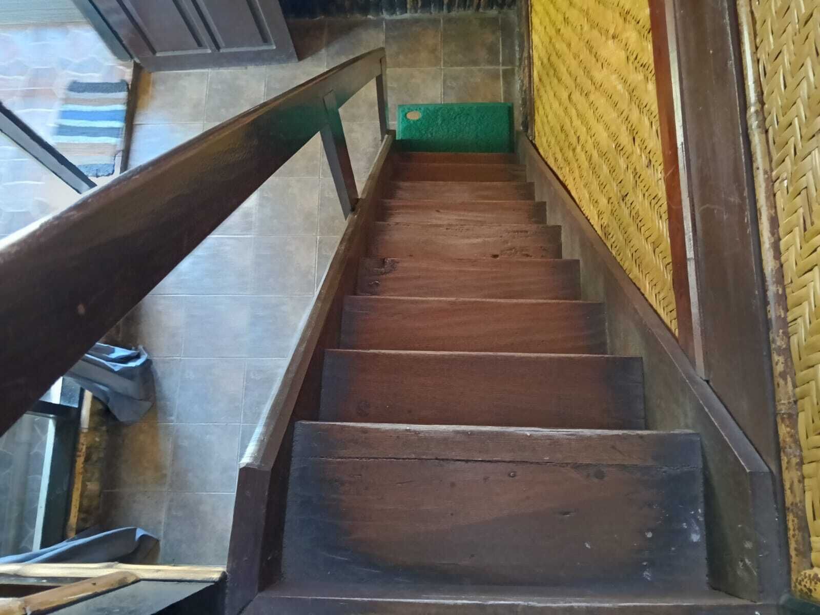 A wooden staircase with a metal handrail and a green carpet at the bottom.